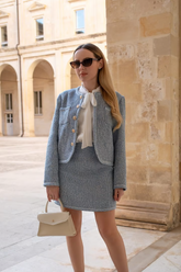a lady in a white shirt. and a blue tweed jacket and  skirt suit
